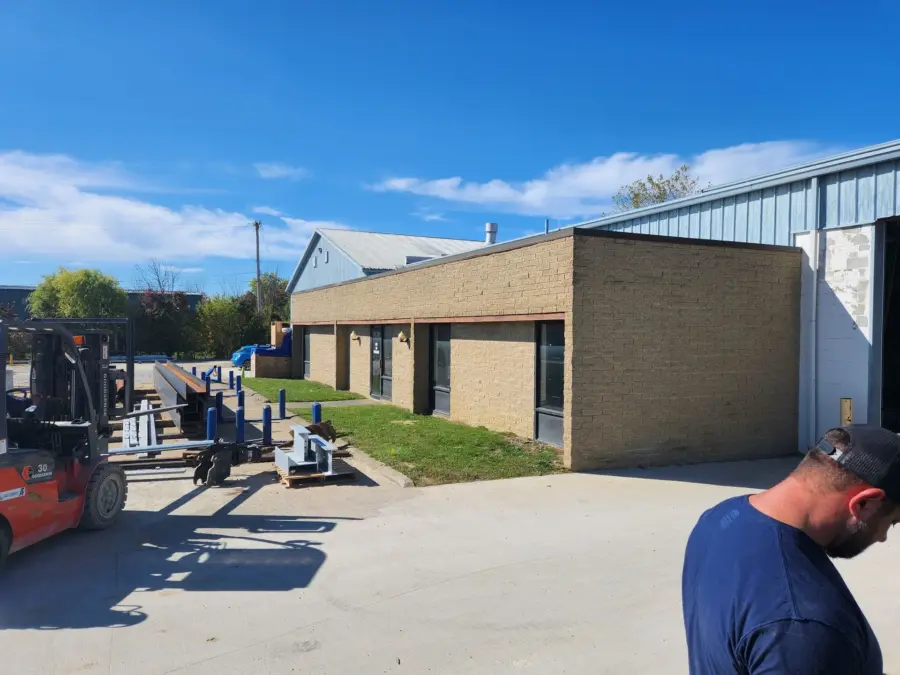 A man is standing in front of a building with a forklift in the background.