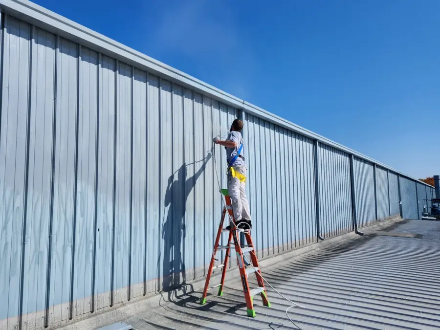 A man is standing on a ladder painting a wall.
