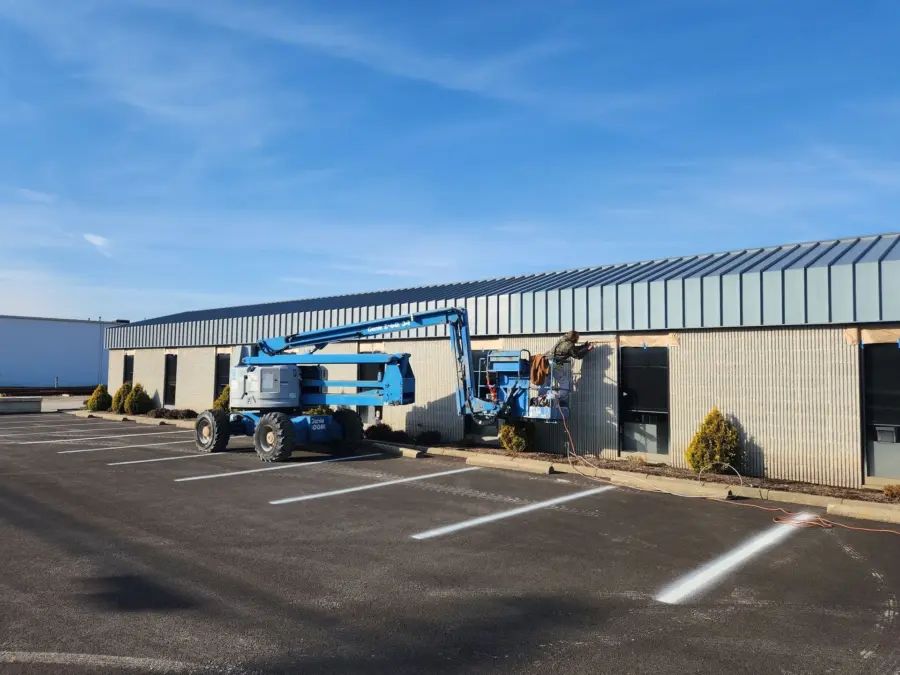 A blue crane is parked in front of a building in a parking lot.