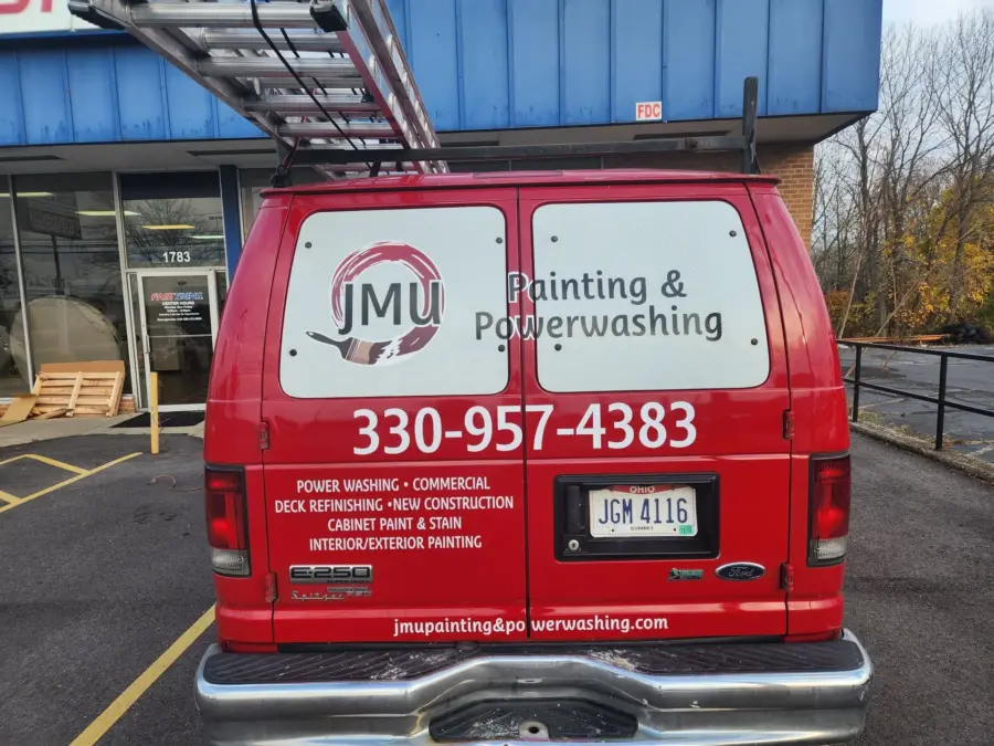 A red van is parked in front of a building advertising painting and powerwashing