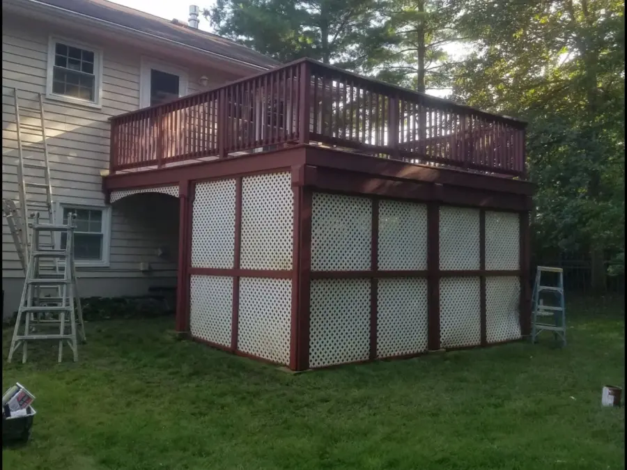 A large deck with a ladder in the backyard of a house.