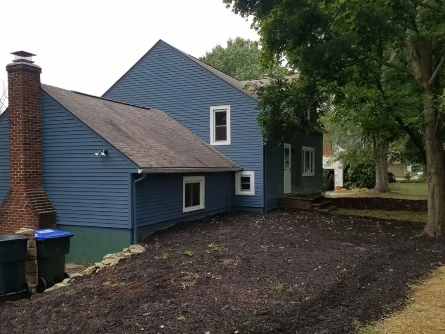 The back of a blue house with a brick chimney