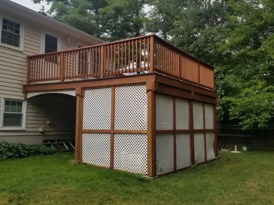 A wooden deck with a screened in area underneath it