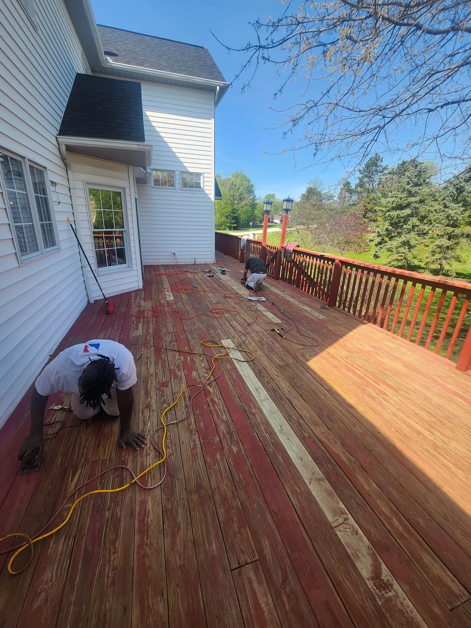 JMU crew sanding and preparing a wooden deck for staining