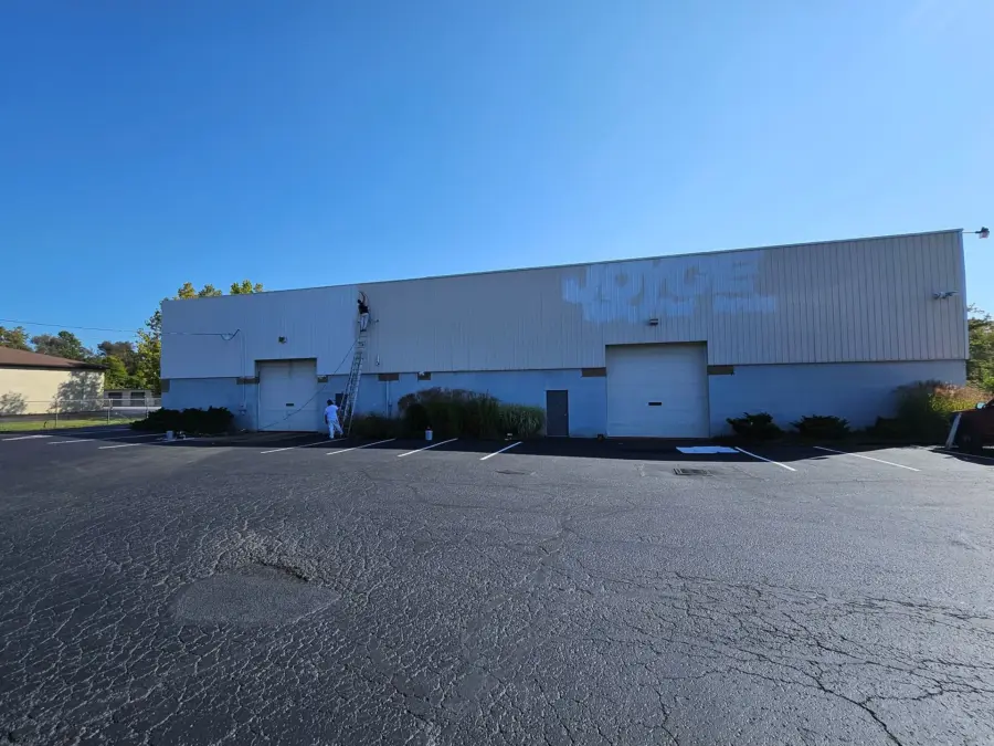A man is standing in front of a large white building