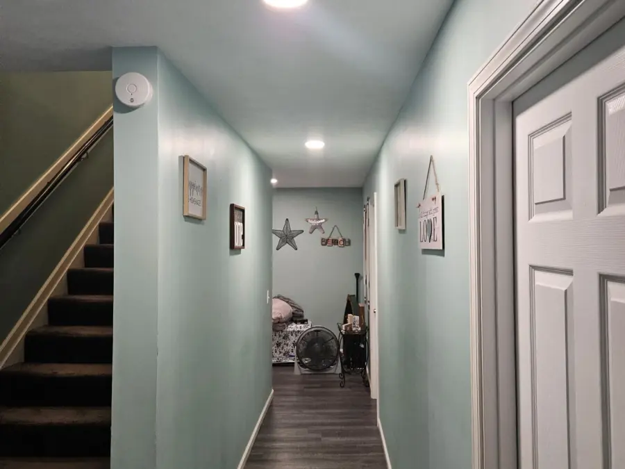 A long hallway with stairs and a door in a house.