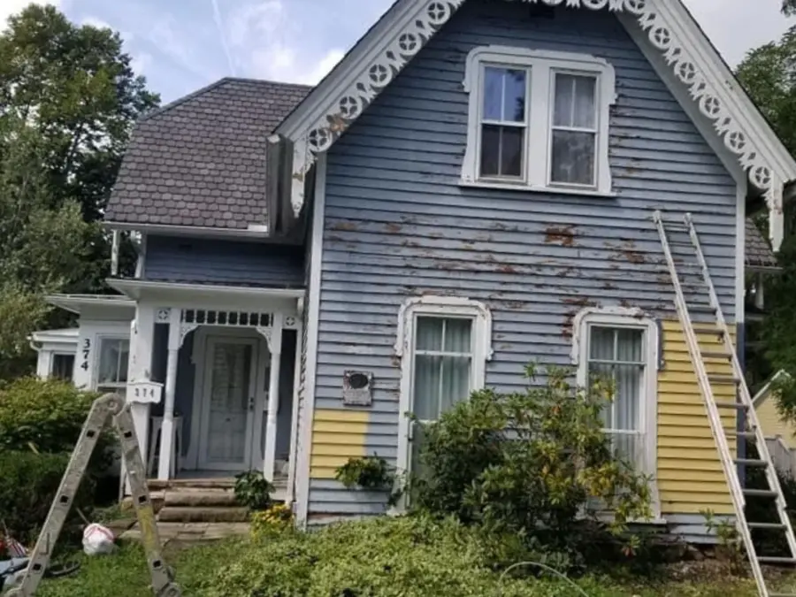 A blue and yellow house with a ladder in front of it.