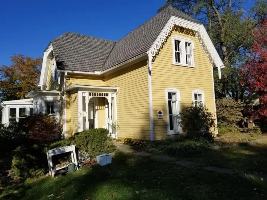 A yellow house with a gray roof and white trim