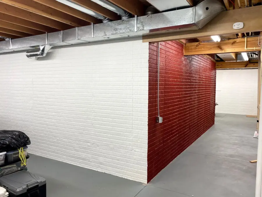 A basement with a red brick wall and white brick walls
