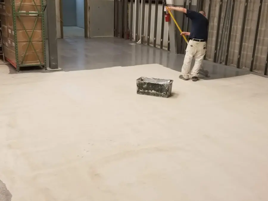 A man is measuring the floor of a building with a tape measure.