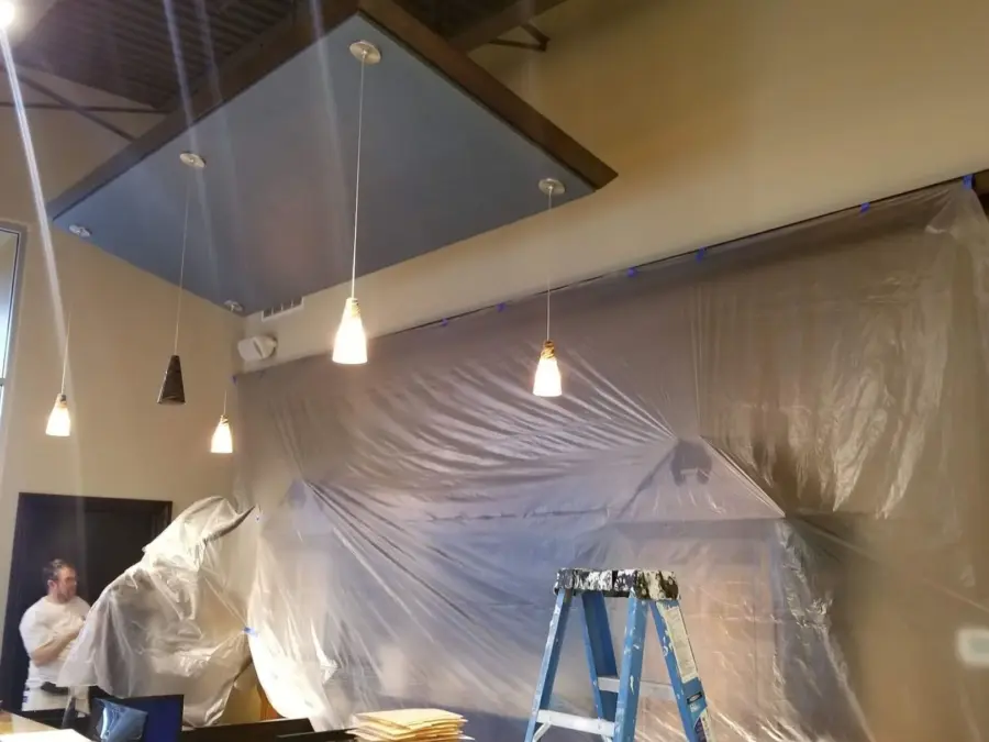 A ladder is sitting in front of a wall that is covered in plastic.