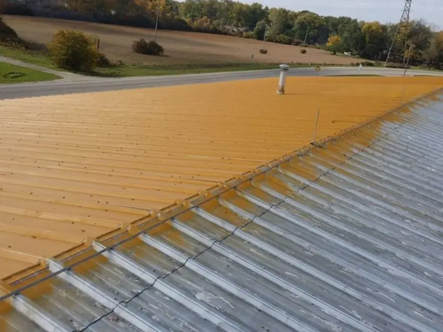 A roof with a lot of rust on it is being painted.