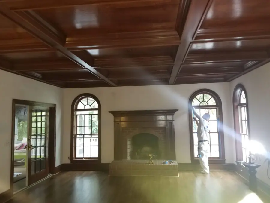 A man is standing in a living room with a fireplace and arched windows