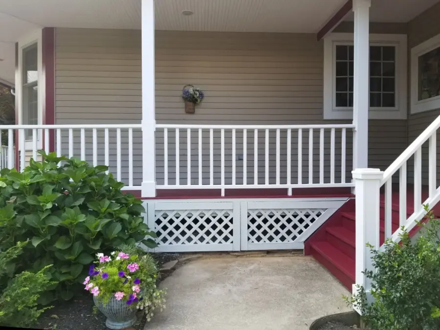 A porch with a white railing and red stairs