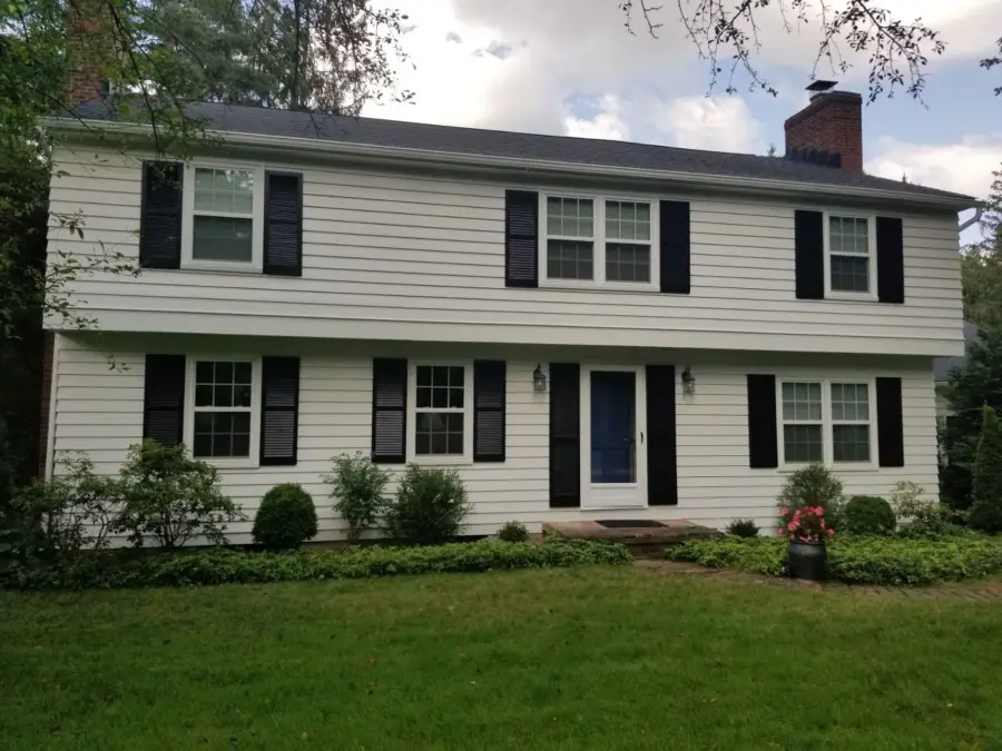 A white house with black shutters and a blue door