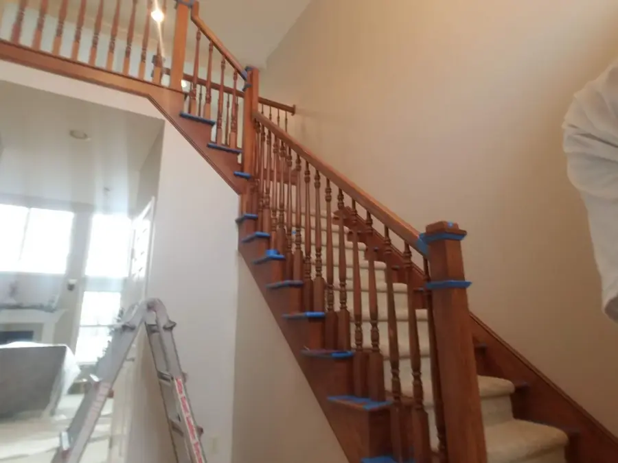 A wooden staircase with blue tape on the railing